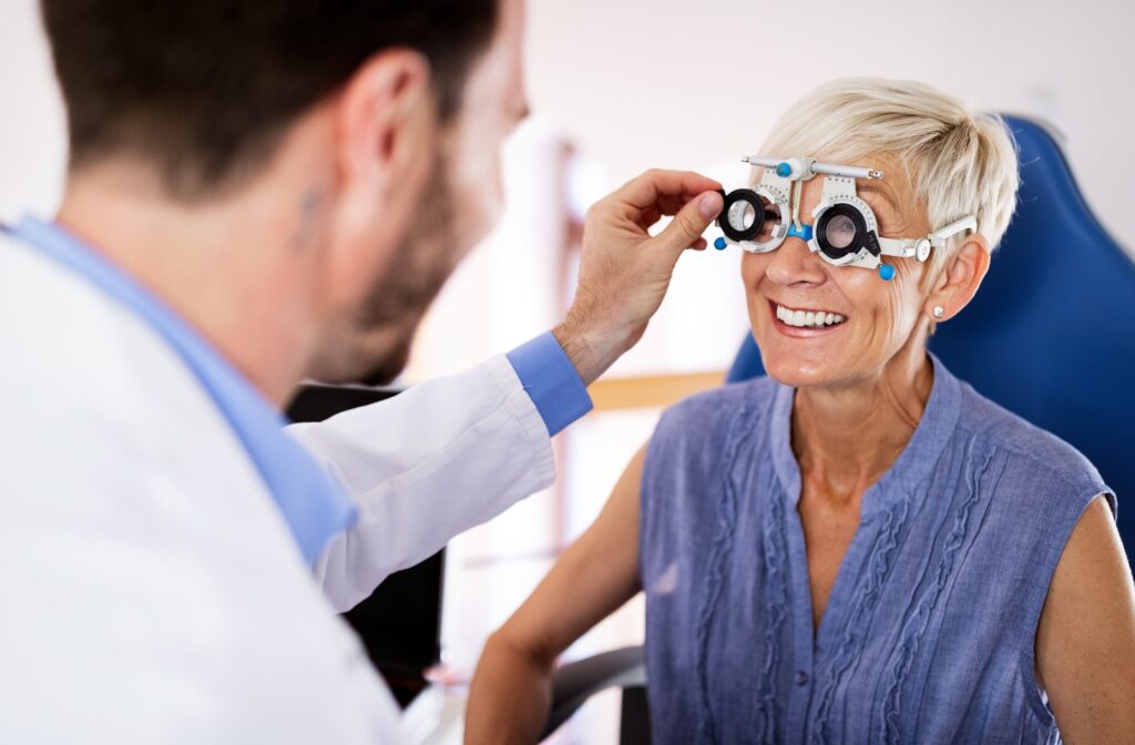Young male optometrist helps adjust a trial frame on a smiling and happy mature patient.