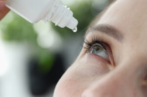 A woman putting Vuity eye drops into her right eye.