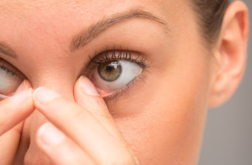 A close-up of a woman rubbing her dry eyes.