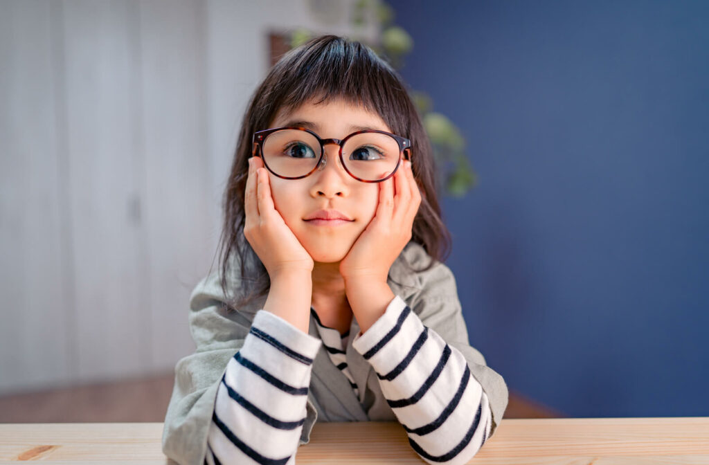 A young girl wearing glasses shows symptoms of amblyopia with her left eye turning inwards.