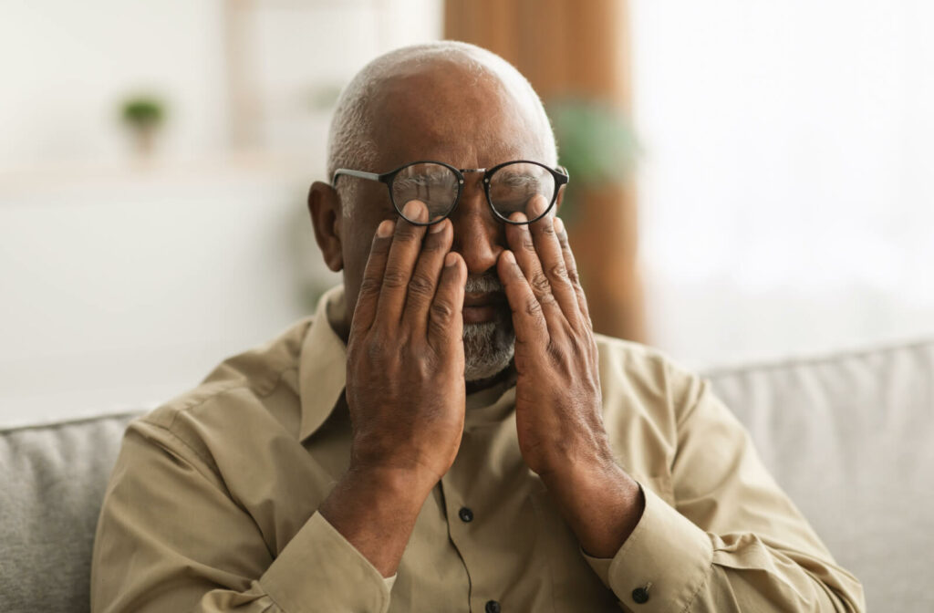 a senior man rubs his eyes to attempt to see, as his vision is fading due to glaucoma