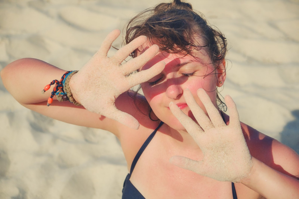 A young girl put her hands in front of her face for protection from the sun. Without proper eye protection can result in ultraviolet keratitis.