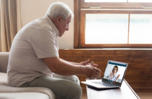 A senior man in his living room undergoing a Telehealth eye exam with his optometrist.
