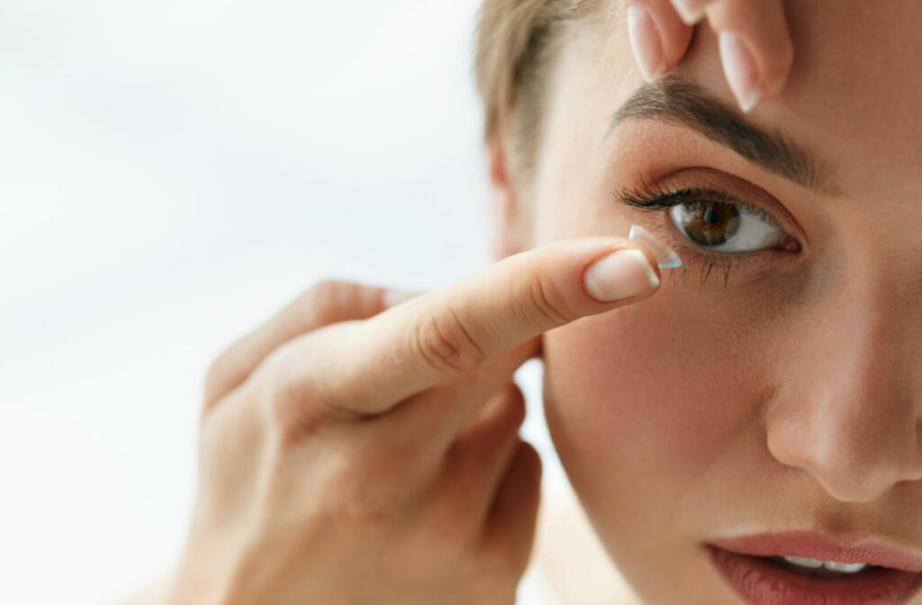 Close-up of a woman using her left index finger to pull her eyelid down while she puts contact lenses on her right eye with her right hand